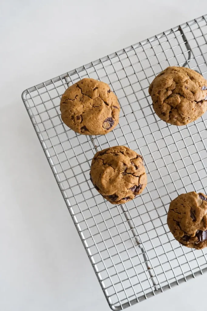 Chocolate chip cookies without eggs cooling on a wire rack, with a soft golden-brown texture and visible dark chocolate chunks.