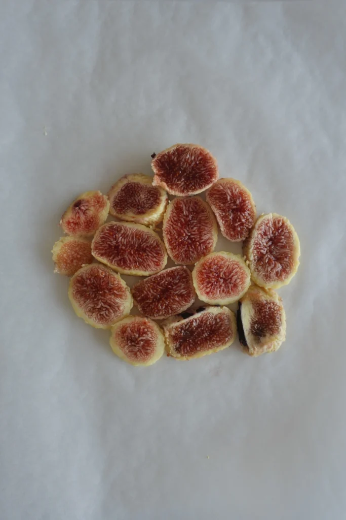 Sliced fresh figs arranged on baking paper, ready to be pressed for the fig carpaccio.
