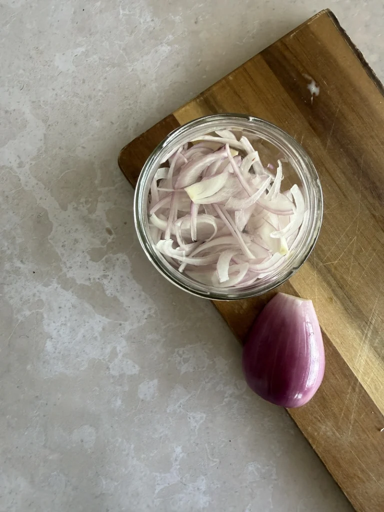 Sliced red onion in a small bowl, prepared as an ingredient for kachumber salad.