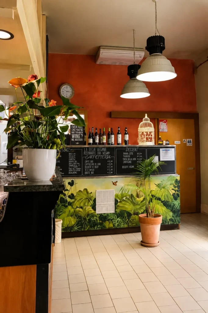 Interior of La Tecia Vegana, a 100% vegan restaurant in Venice, Italy, with plants, pendant lights and the restaurant counter.