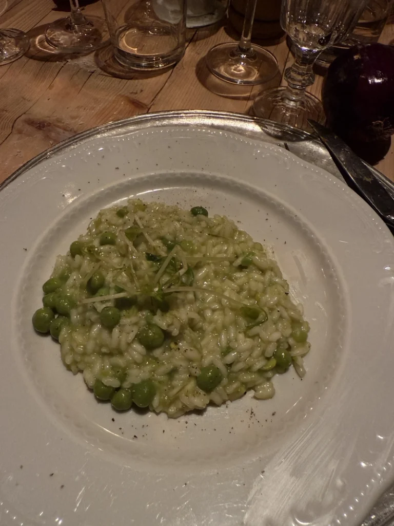 Plate of creamy pea risotto served on a rustic wooden table at Rosa Rosae in the Venetian countryside.