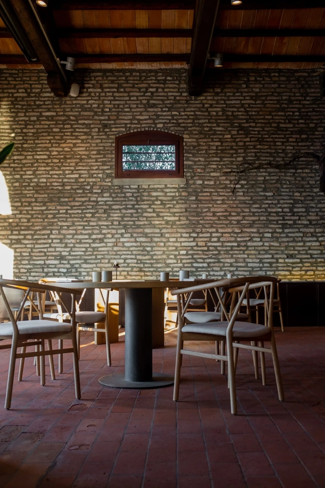 Interior of Venissa restaurant in the Venetian Lagoon, with exposed brick walls, wooden tables and minimalist dining room decor.
