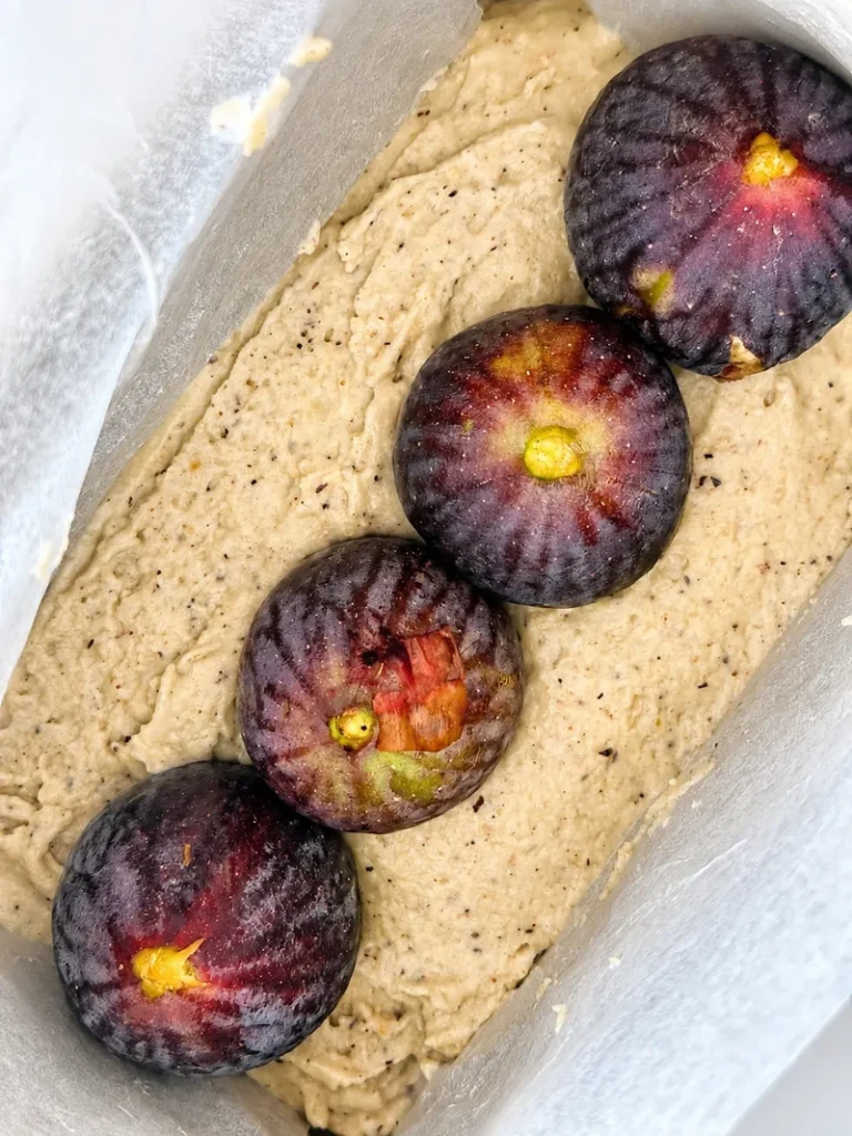 Whole fresh black figs arranged in a continuous row through the centre of the batter for vegan gluten-free fig bread with fresh figs.