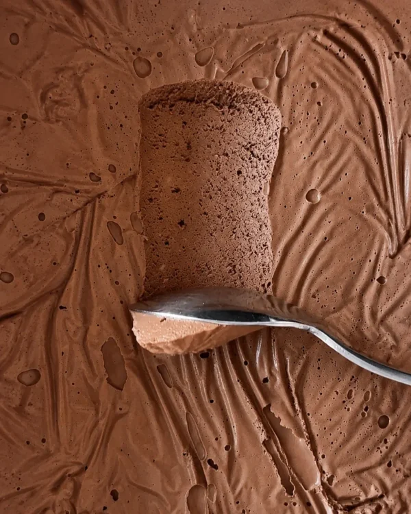 Close up of silken tofu chocolate mousse with a spoon scooping through its thick, airy and creamy texture.