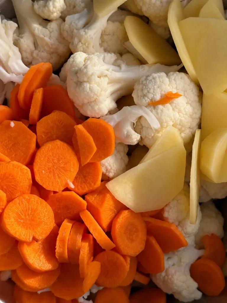 Close up of chopped carrots, cauliflower and potatoes prepared for lemon carrot cauliflower soup.