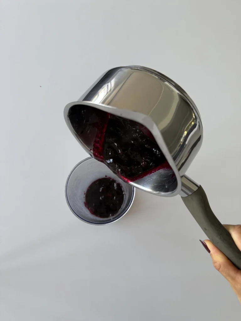 Blueberries being added to a blender to prepare the coulis for vegan panna cotta.