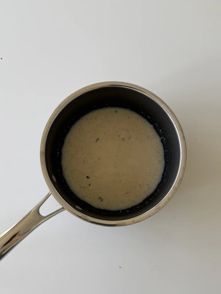 Soy milk and agar agar mixture simmering in a saucepan for vegan panna cotta.