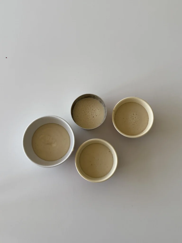 Top view of four molds filled with vegan panna cotta mixture, ready to chill and set.