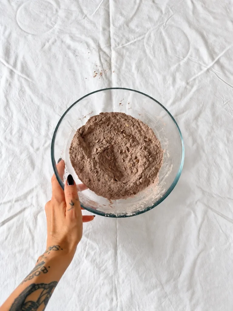 Mixed dry ingredients for vegan chocolate pear cake in a glass bowl during the recipe process.