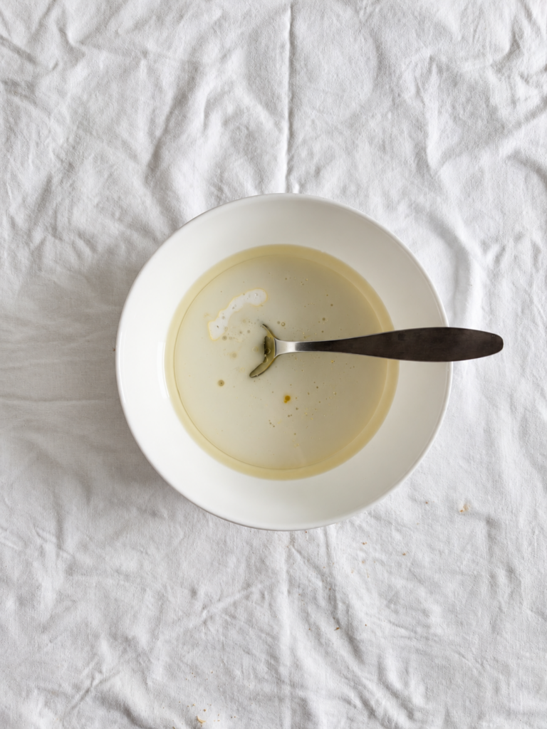Wet ingredients for vegan chocolate pear cake in a white bowl, including plant based milk, maple syrup and oil.