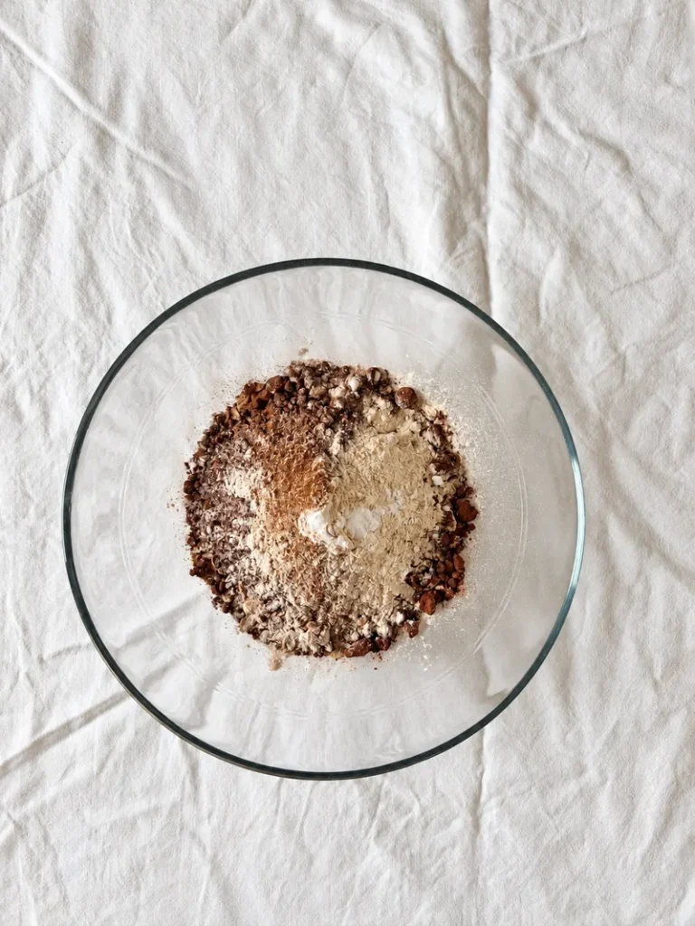 Dry ingredients for vegan chocolate pear cake in a glass bowl, including rice flour, oats, cocoa powder and psyllium husk.