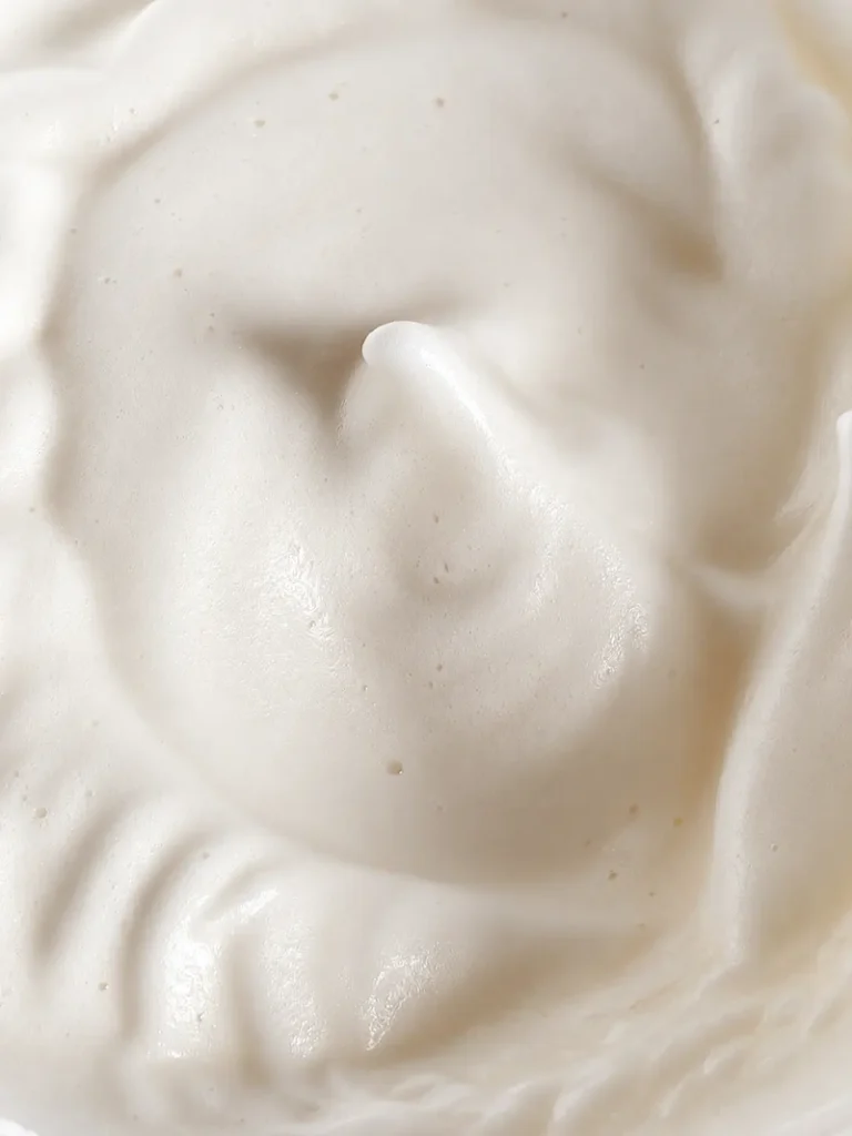 Whipped aquafaba at soft peaks for vegan chocolate pear cake, shown in a close up macro view.